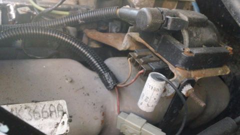 1994 Ford Bronco - This image shows engine parts, including wiring and an electrical component, with some visible text on a label.