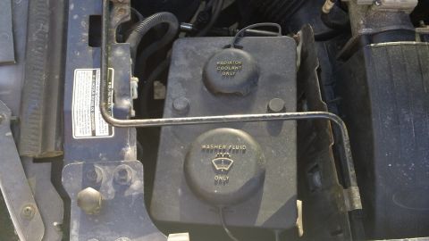 1994 Ford Bronco - Close-up view of engine bay components, including fluid reservoirs, with visible blue paint.