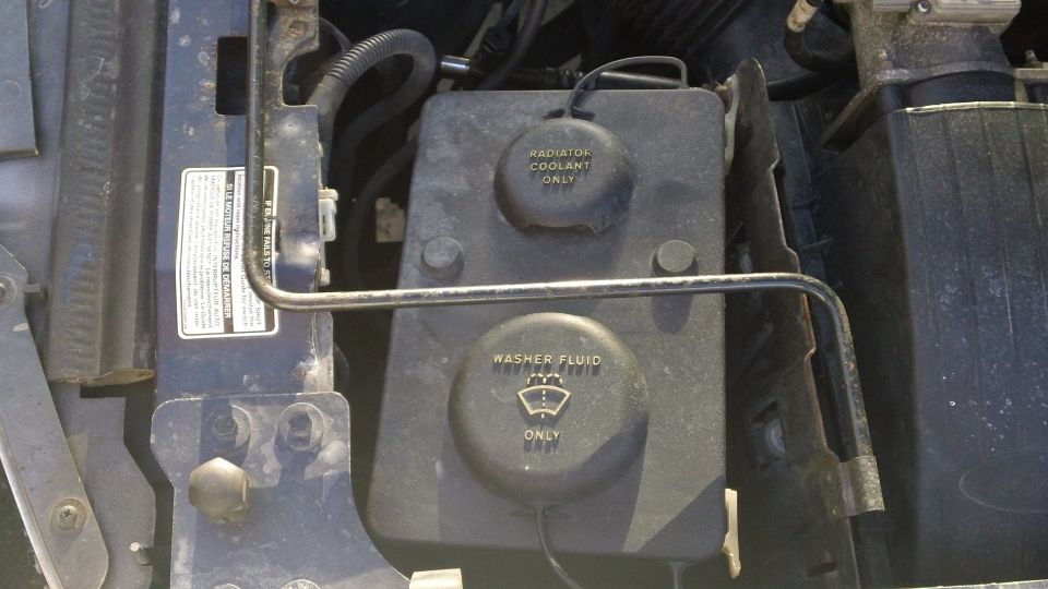 Engine bay with radiator coolant and washer fluid reservoirs. Blue paint visible
