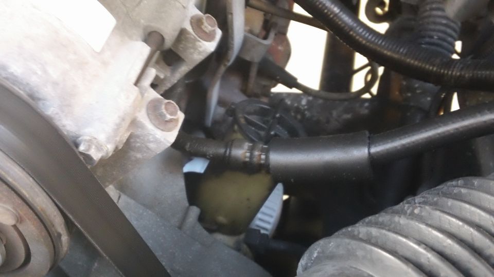 Engine hoses and metal components with a yellow fluid reservoir visible