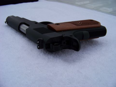 1995 Mercury Grand Marquis - A black pistol with textured wood grips is shown from a top-down perspective on a white surface.