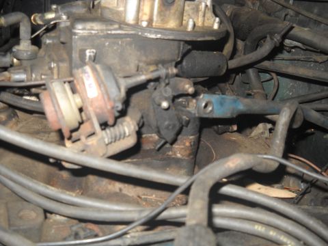 1982 Ford Bronco - Close-up view of a vehicle's engine carburetor, highlighting its mechanical components and wear.