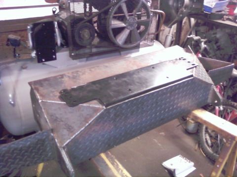 1989 Ford Bronco - A large air compressor is visible behind a custom-built metal structure with diamond plate accents.