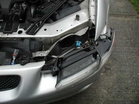 2002 Pontiac Grand Prix - Front headlight assembly removed from a silver car, revealing the engine bay and electrical connections.