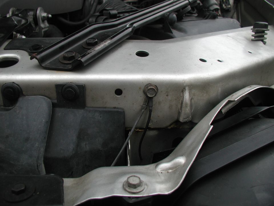 Close-up of metal brackets and wiring in a car's engine bay