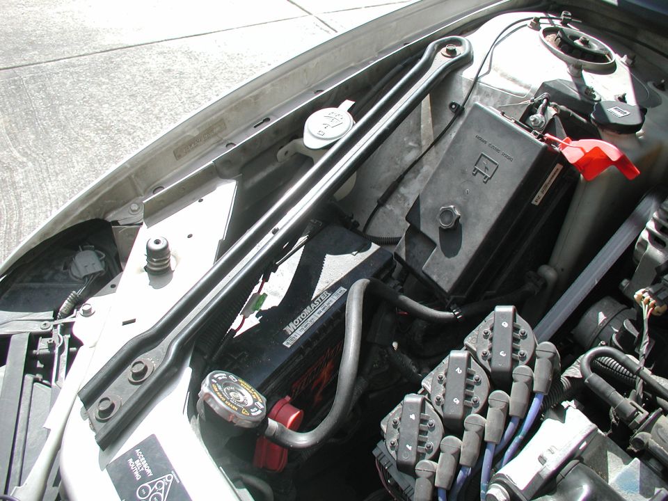 Engine bay view showing battery, fuse box, and spark plug wires