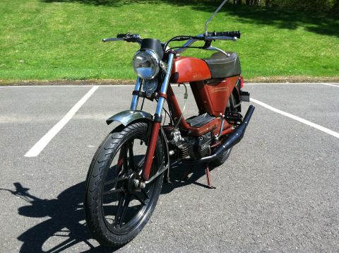 1981 Garelli Rally Sport - A red moped is parked in a lot, with a grassy area and trees visible behind it.