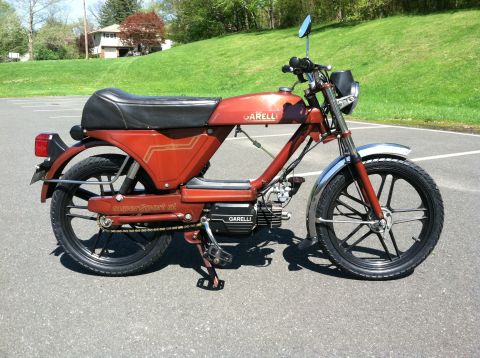 1981 Garelli Rally Sport - This red Garelli moped features a black seat, black wheels, and the 'Garelli' logo on the fuel tank.
