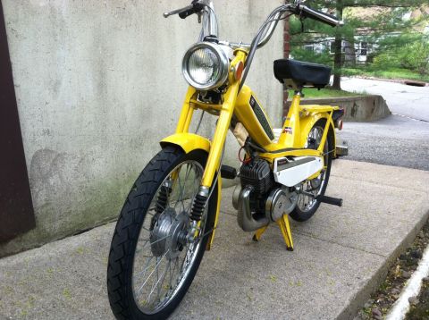 1981 Garelli Rally Sport - A yellow moped is parked on a concrete surface, showing its front wheel, engine, and handlebars.