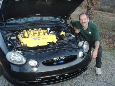 1997 Ford Taurus - A man poses with a car a custom yellow Yamaha V8 engine under the hood.