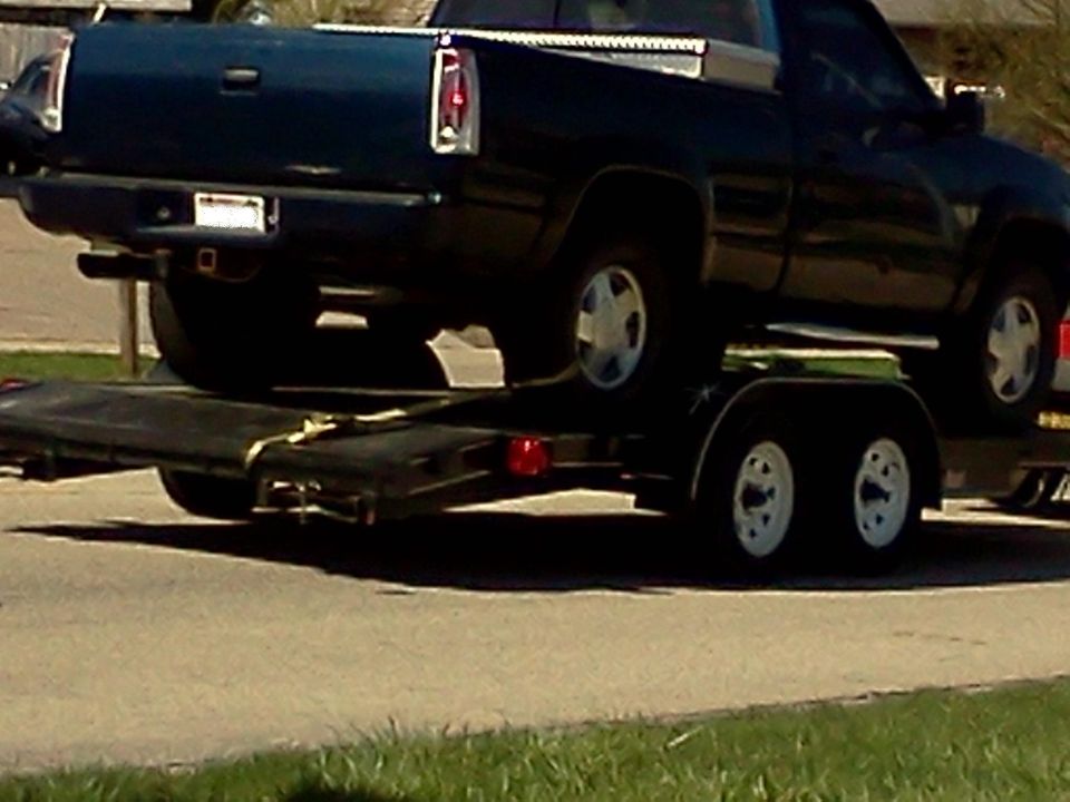 dark blue pickup truck being towed on a trailer