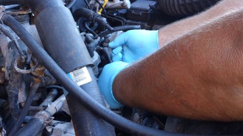 1994 Ford Bronco - Working on engine hoses, part number visible on a hose.