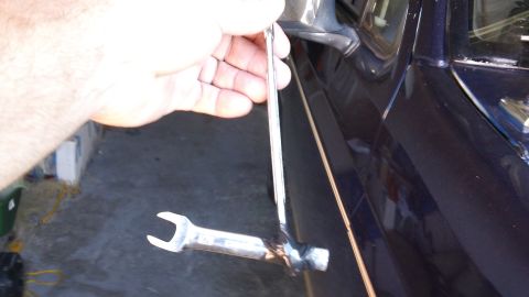 1994 Ford Bronco - A hand holds a wrench near the side of a dark blue vehicle, with a Supermotors watermark visible.