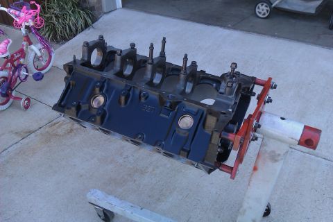 1996 Chevrolet Camaro - A black engine block, identified by the '327' casting, is secured to an engine stand outdoors.