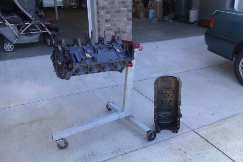 1996 Chevrolet Camaro - Engine block and oil pan displayed on a stand in a garage setting.