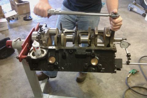 1996 Chevrolet Camaro - Mechanic uses a torque wrench on an engine block assembly with a dial indicator attached.