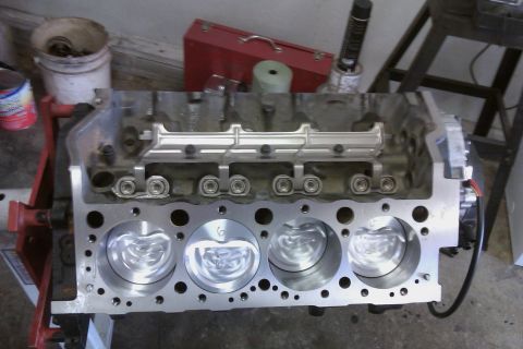 1996 Chevrolet Camaro - A close-up view of an engine block with pistons installed, resting on an engine stand.