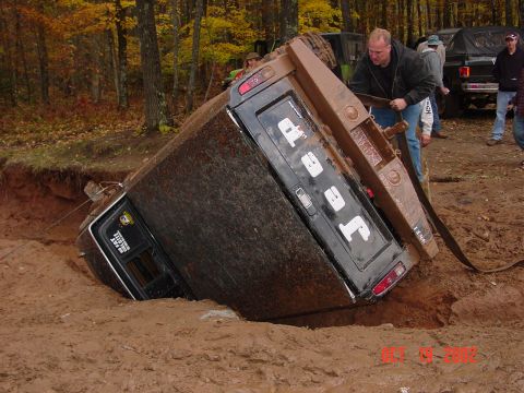 1986 Jeep J-10 - A Jeep J-10 truck is stuck in a deep mud pit while onlookers attempt a recovery.