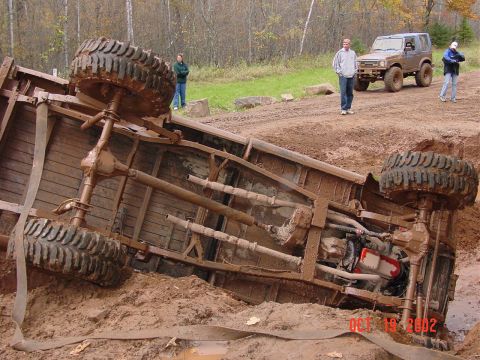 1986 Jeep J-10 - Pickup truck overturned in mud with another SUV in the background.