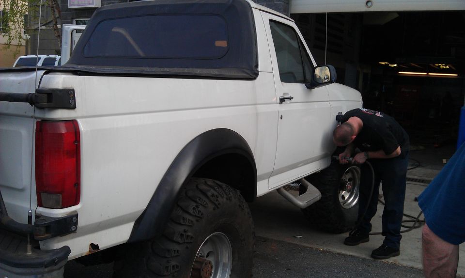 White pickup truck with soft top, man working on front tire