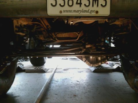 1996 Ford Bronco - A low-angle shot reveals the complex undercarriage of a vehicle, including its suspension and exhaust system.