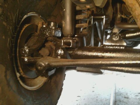 1996 Ford Bronco - Close-up view of a vehicle's greasy suspension and tire assembly.