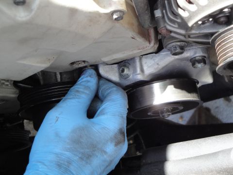 1995 Ford Taurus - Close-up of a hand working on a car's engine pulley system.
