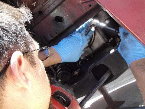 1995 Ford Taurus - A person is performing maintenance on a vehicle's engine compartment.