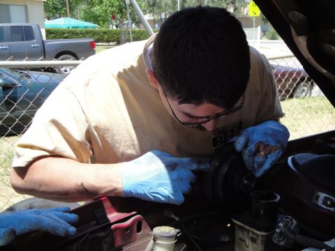 1995 Ford Taurus - Mechanic inspects a component within the engine bay of a vehicle.