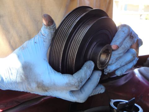 1995 Ford Taurus - A person is holding a crankshaft pulley, which is a component of a vehicle's engine.
