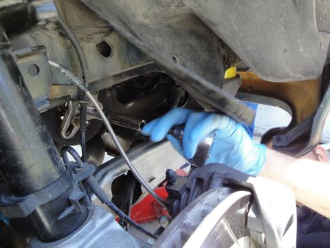 1995 Ford Taurus - Mechanic works on the undercarriage of a vehicle, focusing on the brake system.