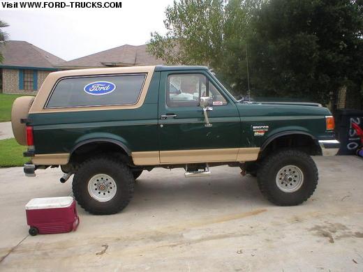 Green and tan lifted Ford Bronco SUV parked in profile on a driveway