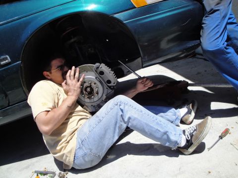 1995 Ford Taurus - Mechanic works on a car's brake system, focusing on the rotor and caliper.
