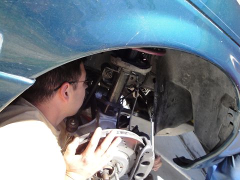 1995 Ford Taurus - A person is working on the suspension system of a vehicle, focusing on the brake assembly.