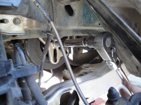 1995 Ford Taurus - Close-up view of a vehicle's engine crankshaft pulley being worked on with a socket wrench.