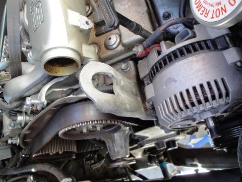 1995 Ford Taurus - A close-up view of engine components, focusing on the alternator and timing belt system.