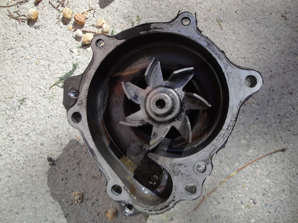 Used car water pump with visible impeller and housing, resting on concrete