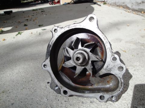 1995 Ford Taurus - A worn water pump with a rusted impeller is shown resting on a concrete surface.