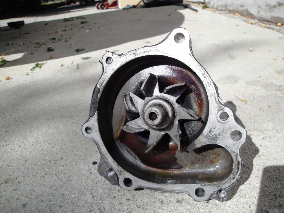 Used car water pump with a corroded impeller, sitting on concrete