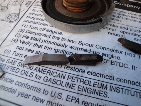 1995 Ford Taurus - A radiator cap and two metal engine parts are placed on top of a page from an engine manual.