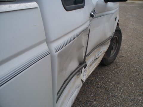 1992 Ford F-250 - Driver's side door and fender of a 1992 Ford F-250 show significant collision damage.