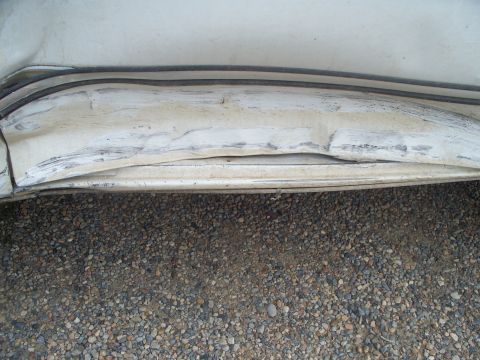 1992 Ford F-250 - This photo shows significant damage to a vehicle's lower body panel, with visible dents and scuffs.