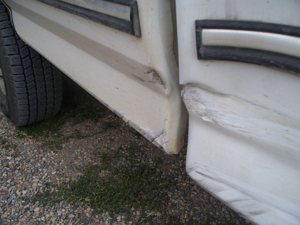 Damaged white lower body panel and tire on a vehicle