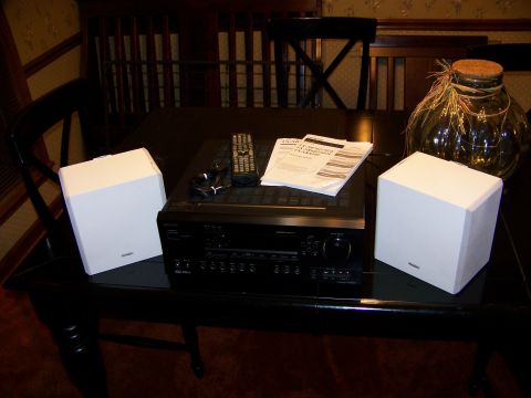 1992 Jeep YJ - An audio receiver, remote, and two white speakers are arranged on a dark table with a decorative jar in the background.