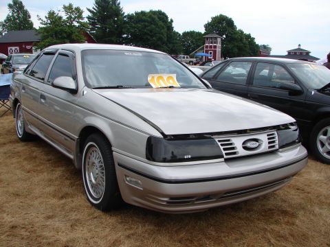 1992 Ford Taurus - A silver 1992 Ford Taurus is parked on a grassy field, with another car visible behind it.