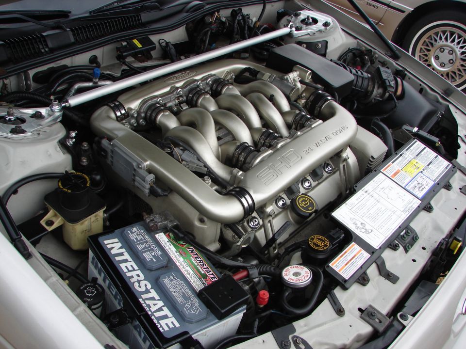 Engine bay of a 1992 Ford Taurus SHO, showing the 3.2L V6 engine, Interstate battery, and various fluid reservoirs
