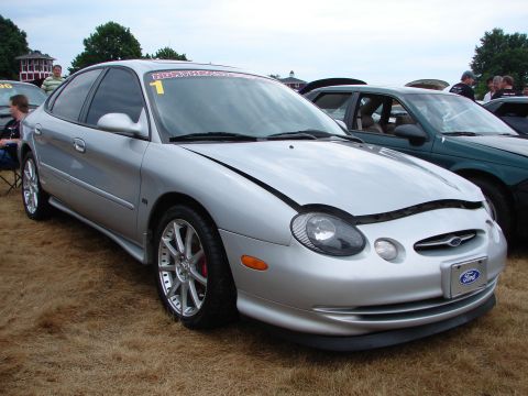 1992 Ford Taurus - Silver sedan with hood open at an outdoor car event. Another vehicle is visible in the background.