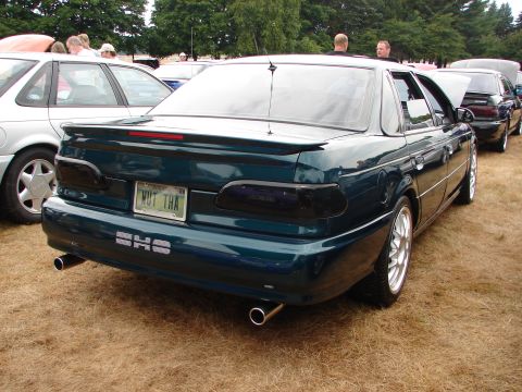 1992 Ford Taurus - A dark green 1992 Ford Taurus SHO is parked outdoors with other vehicles.