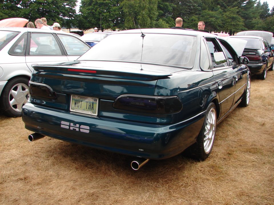 Rear of dark green Ford Taurus SHO sedan with SHO badge and dual exhaust at car show