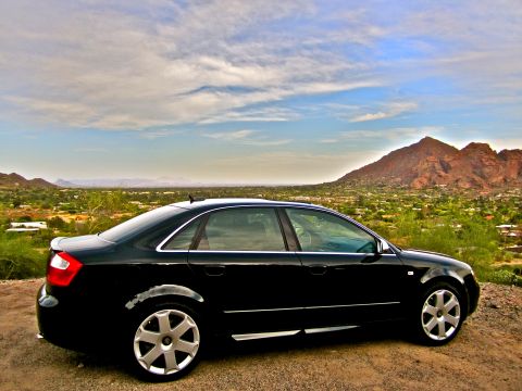 2005 Audi S4 - A black 2005 Audi S4 is parked on a dirt road overlooking a valley with mountains under a cloudy sky.